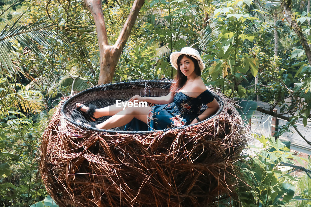 Portrait of smiling woman sitting in wicker container