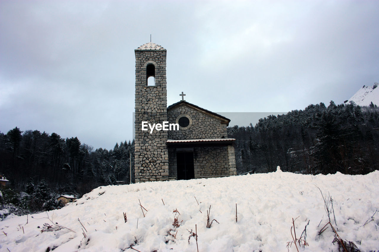 Rustic provincial stone church in the cold of the white snow in the mountains in tuscany