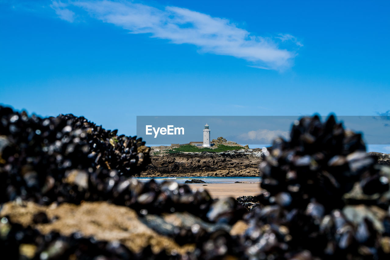 Lighthouse on rock formation against sky