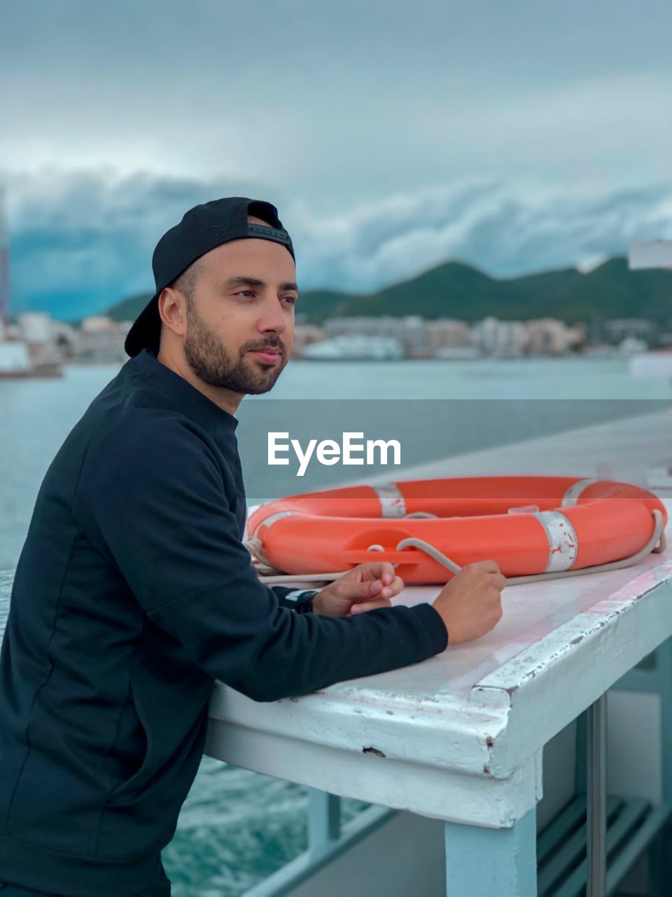 Young man standing in boat against sky