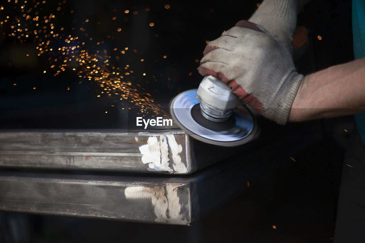 Metal processing. grinder in hand. worker holds tool. creation of steel structure. work in garage.