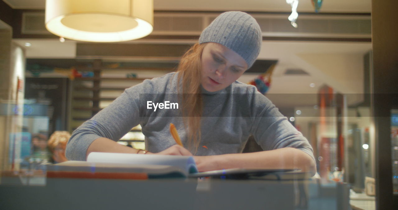 YOUNG WOMAN LOOKING DOWN AT TABLE