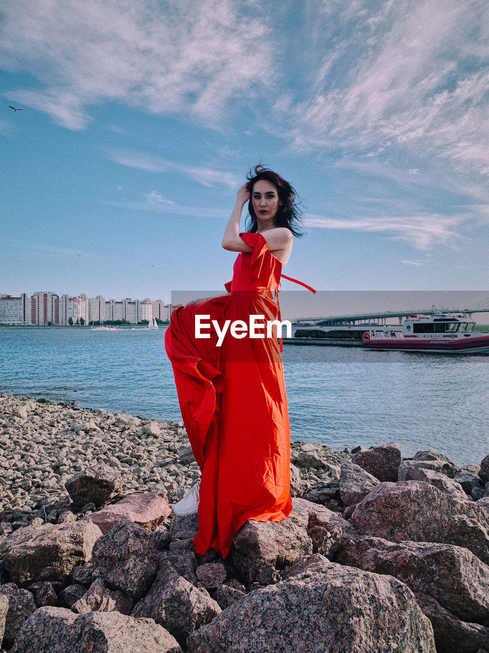 WOMAN STANDING ON ROCK AGAINST SEA