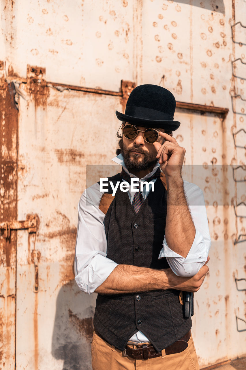 Man wearing hat standing against wall