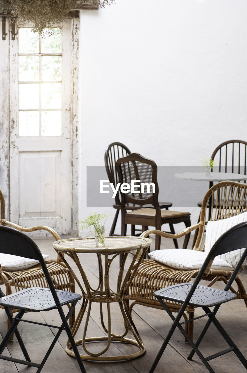 EMPTY CHAIRS AND TABLE IN RESTAURANT AGAINST WALL