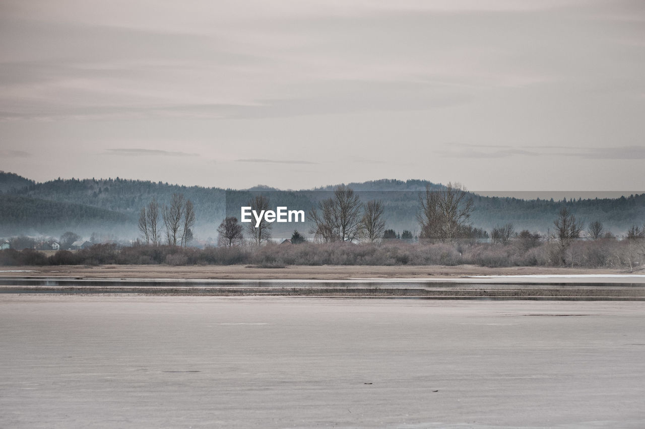 Scenic view of lake against sky during winter