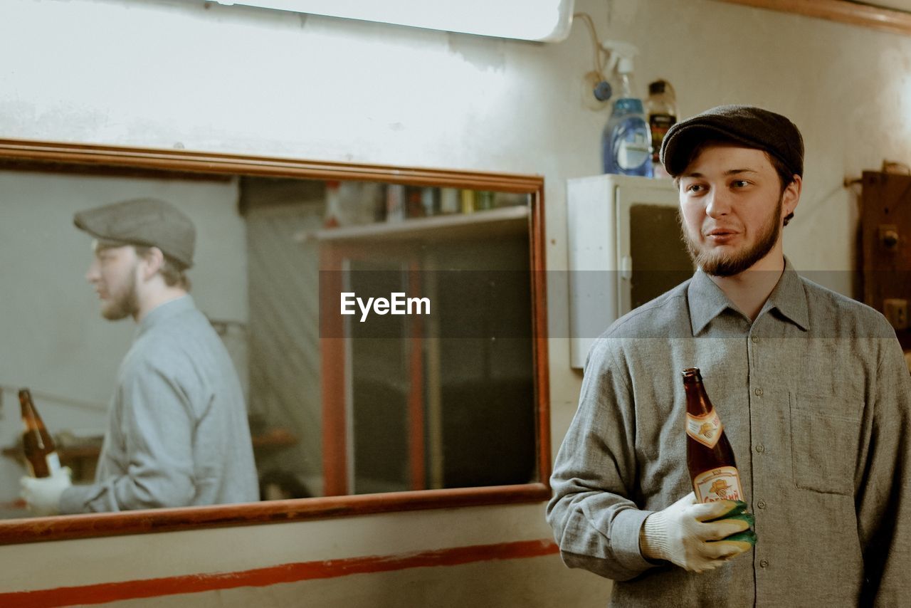 PORTRAIT OF MAN STANDING BY WINDOW