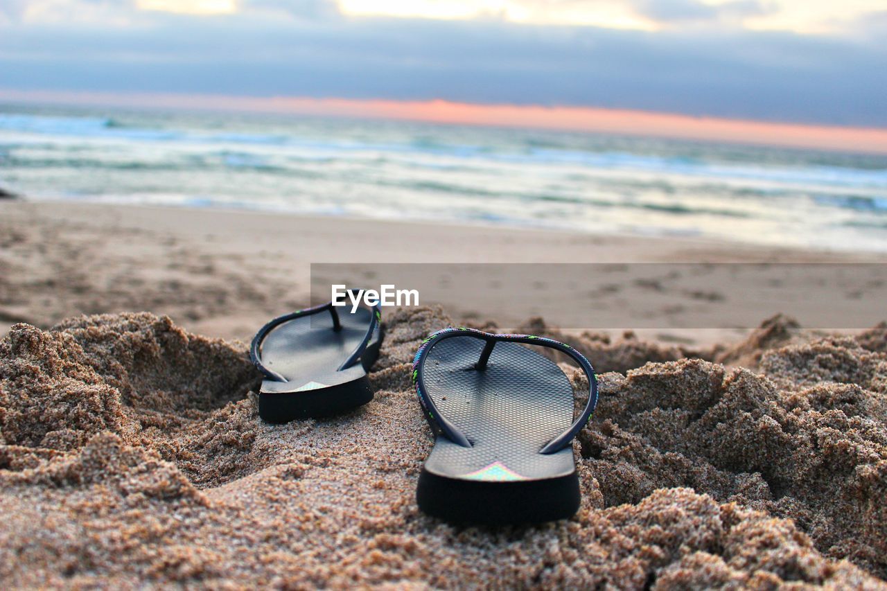 Close-up of sunglasses on sand at beach against sky