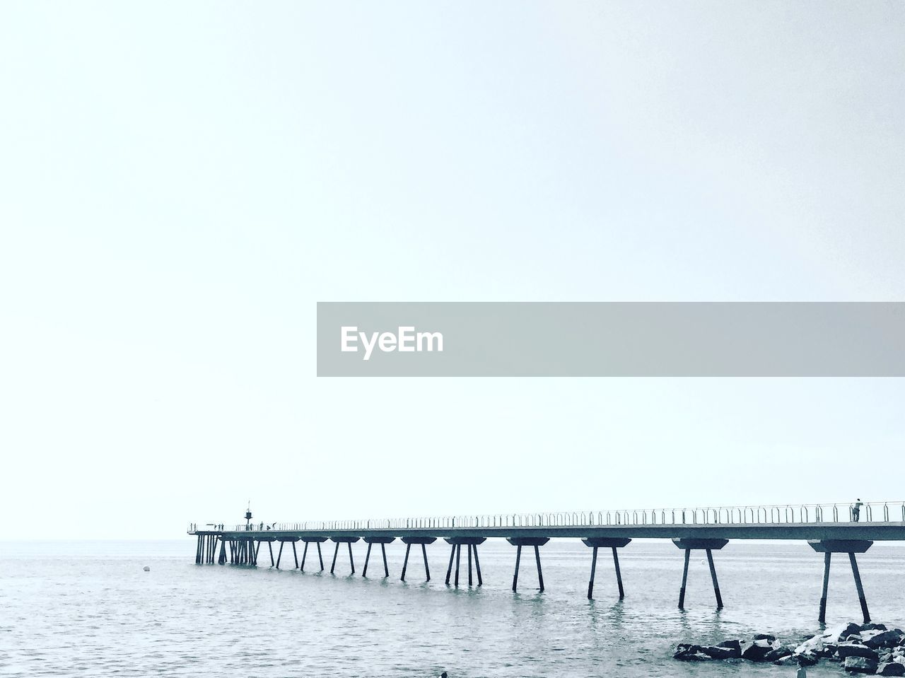 WOODEN POSTS ON PIER OVER SEA AGAINST CLEAR SKY