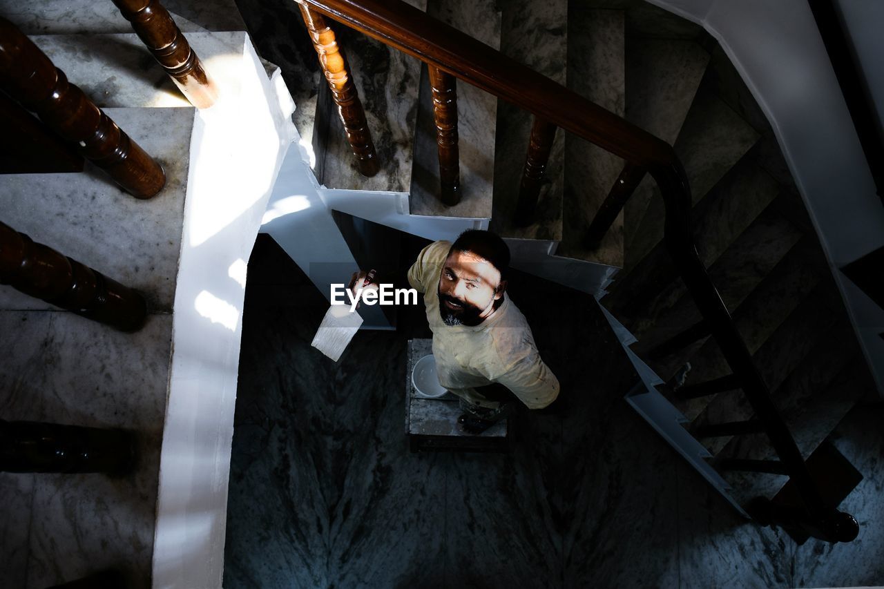High angle view portrait of man painting staircase
