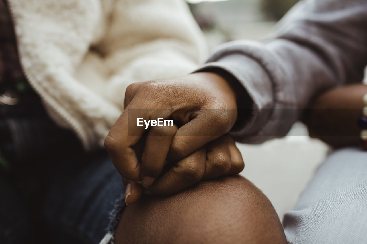 Cropped image of female friends holding hands outdoors