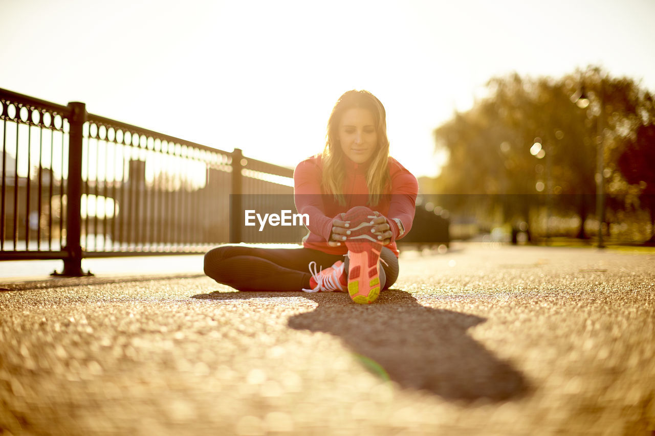 A portrait of a female runner stretching during her pre-run warmups.