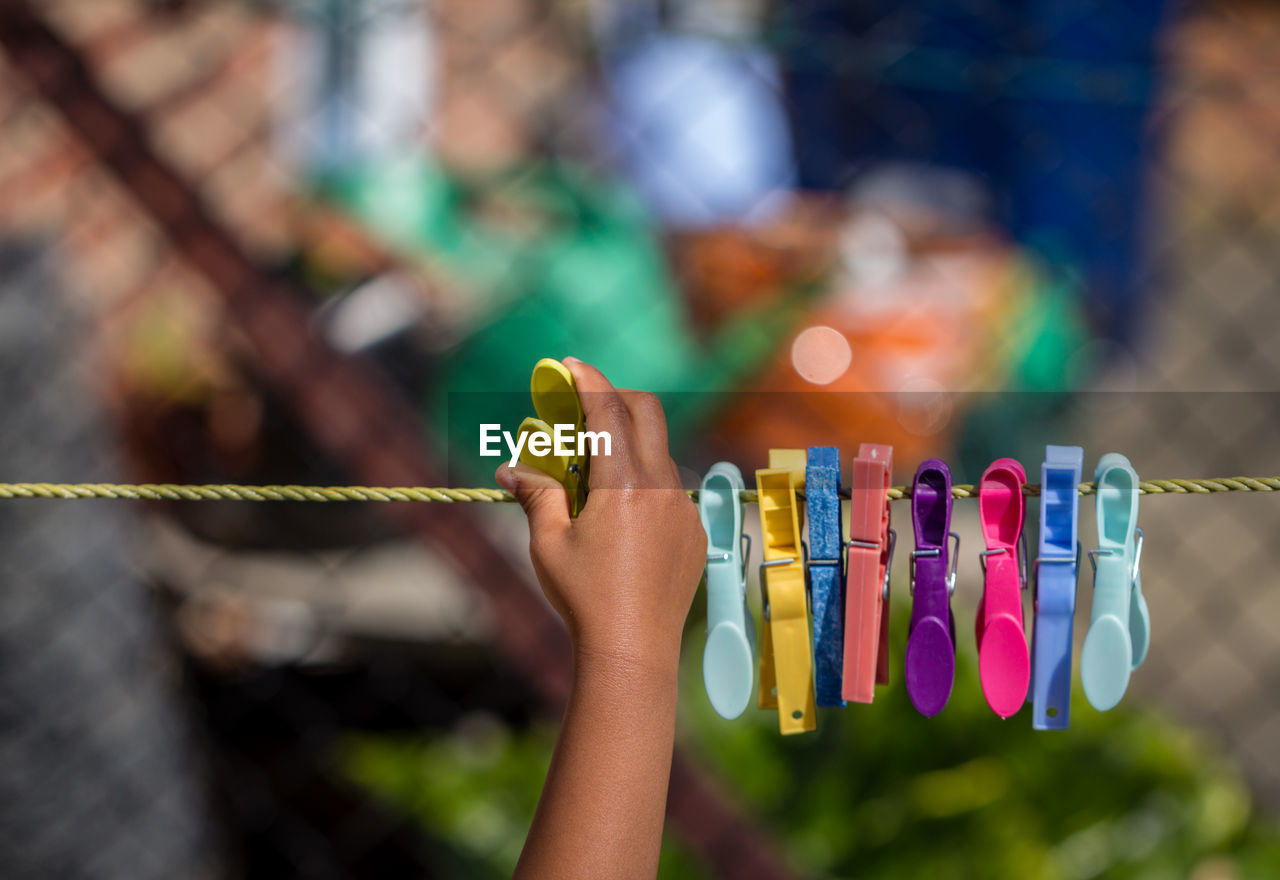 Cropped image of hand pinning clothespin on clothesline