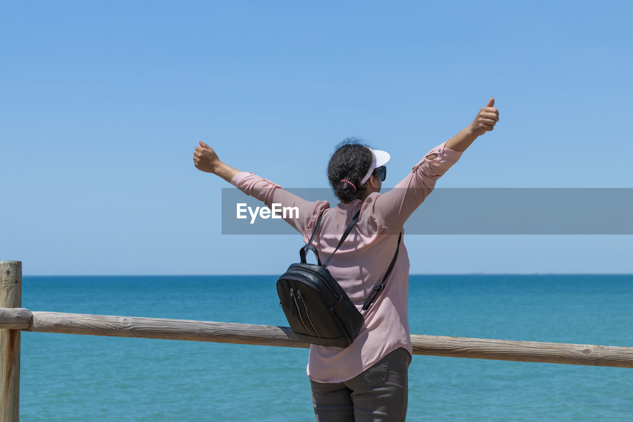 Energetic looking woman stretching towards the sea