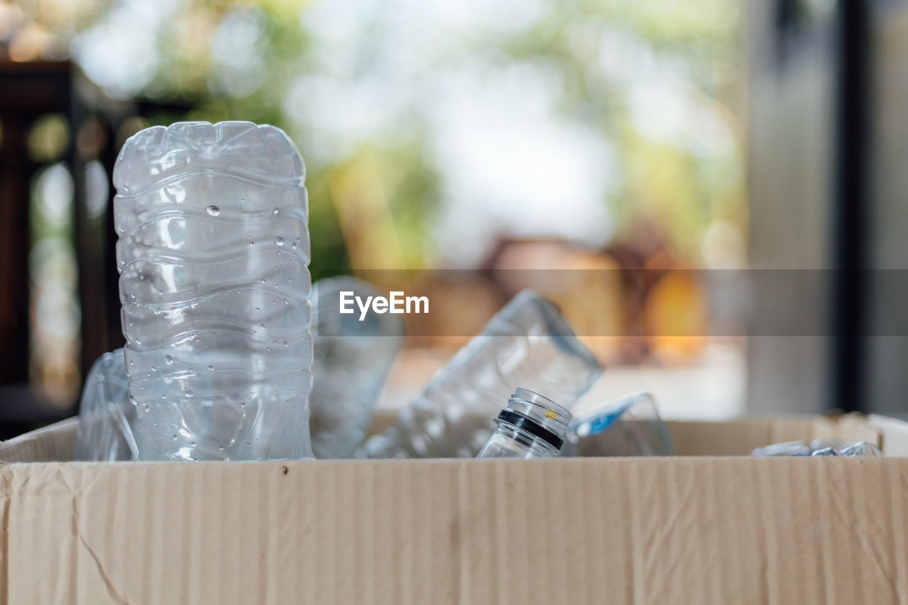 CLOSE-UP OF GLASS BOTTLE ON TABLE AGAINST BLURRED BACKGROUND