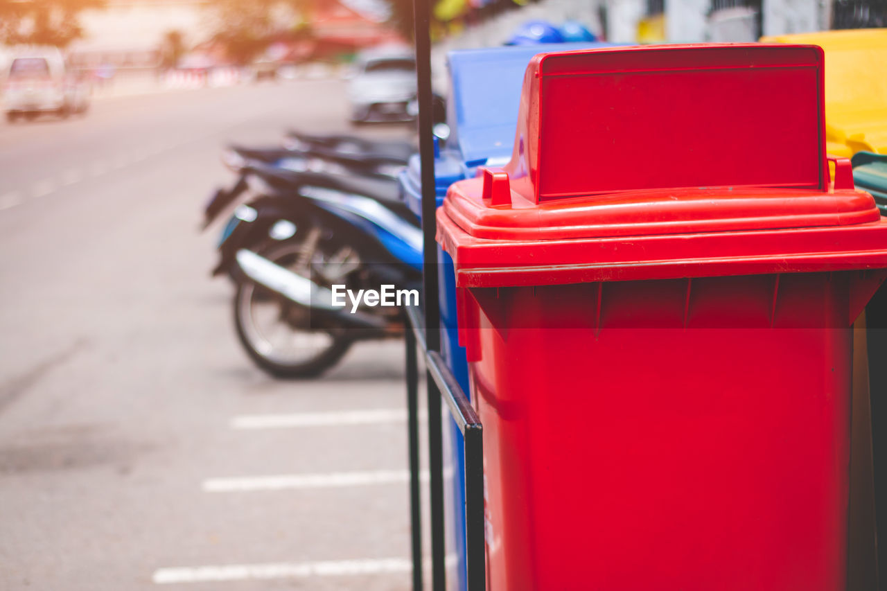 Red garbage can by road