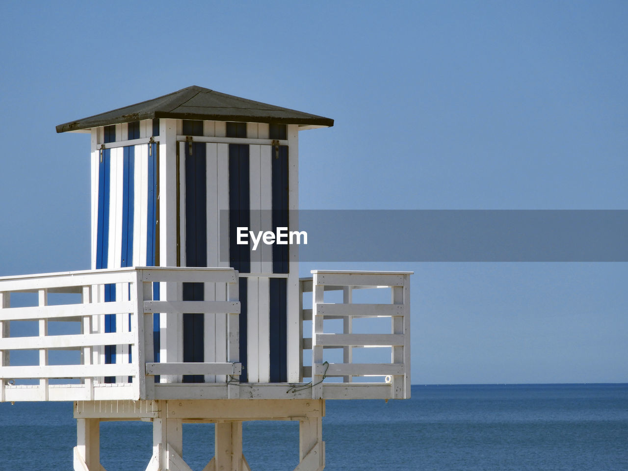 Built structure by sea against clear blue sky