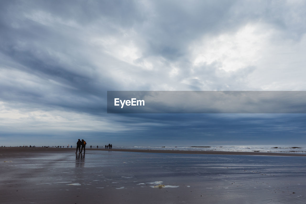 PEOPLE ON BEACH AGAINST SKY