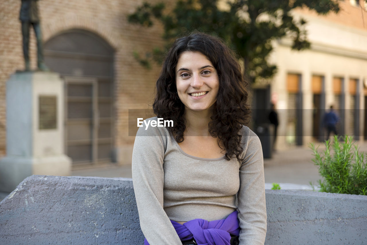 Woman smiling while posing outdoors at the street.