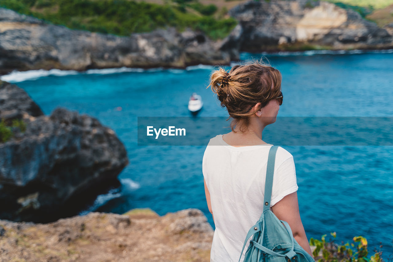 Woman looking at sea while standing on cliff