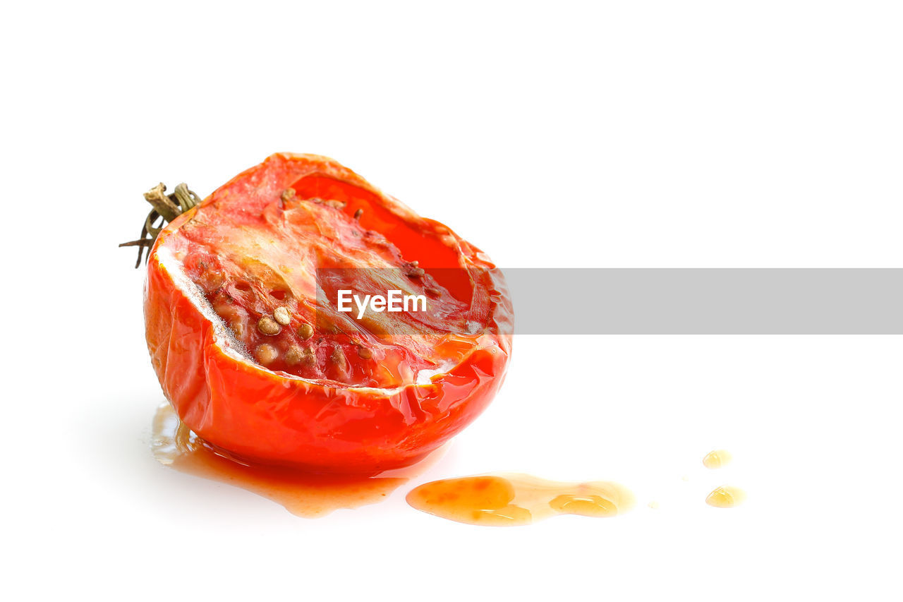 Rotten tomato with juice isolated on white background