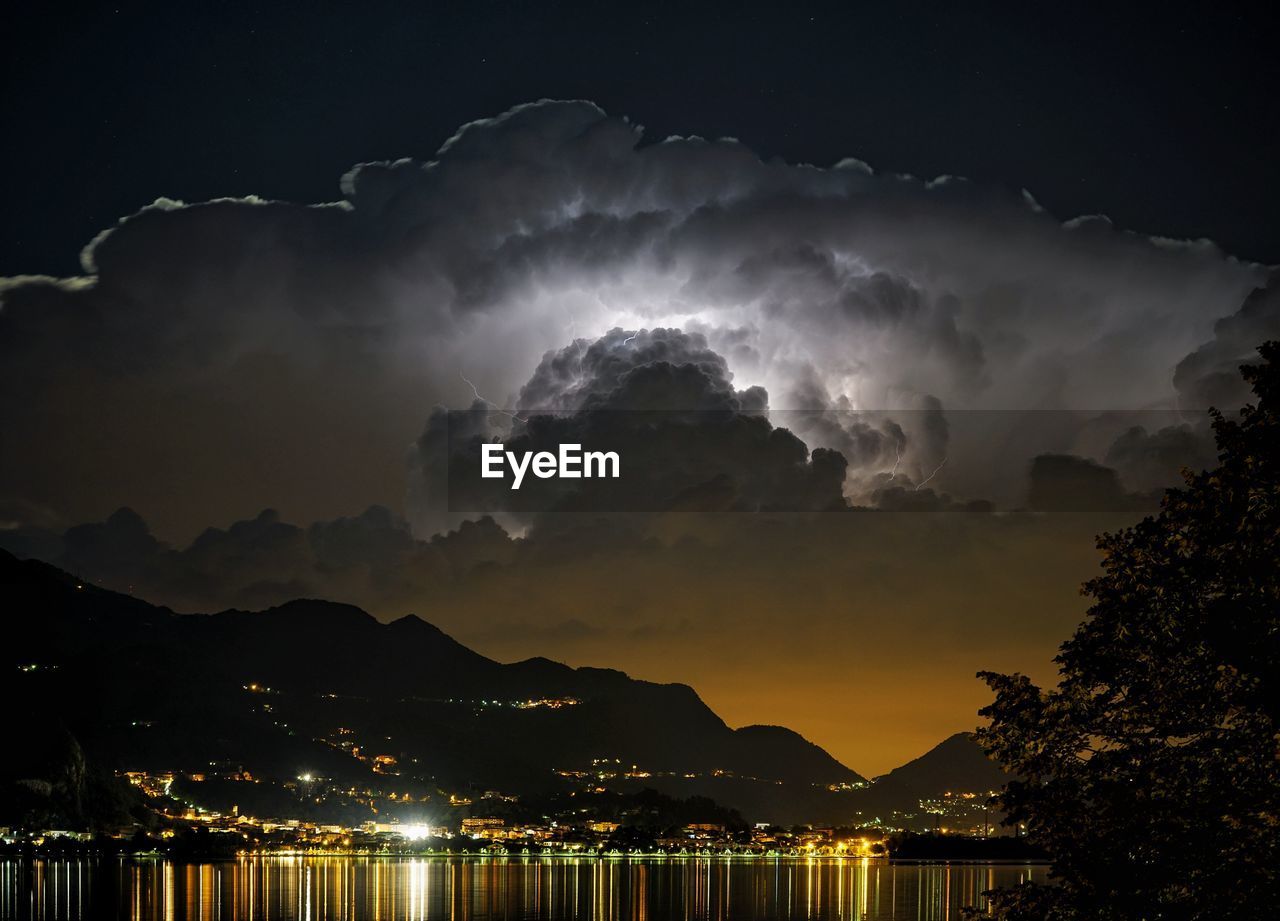 Illuminated town at night with dramatic sky