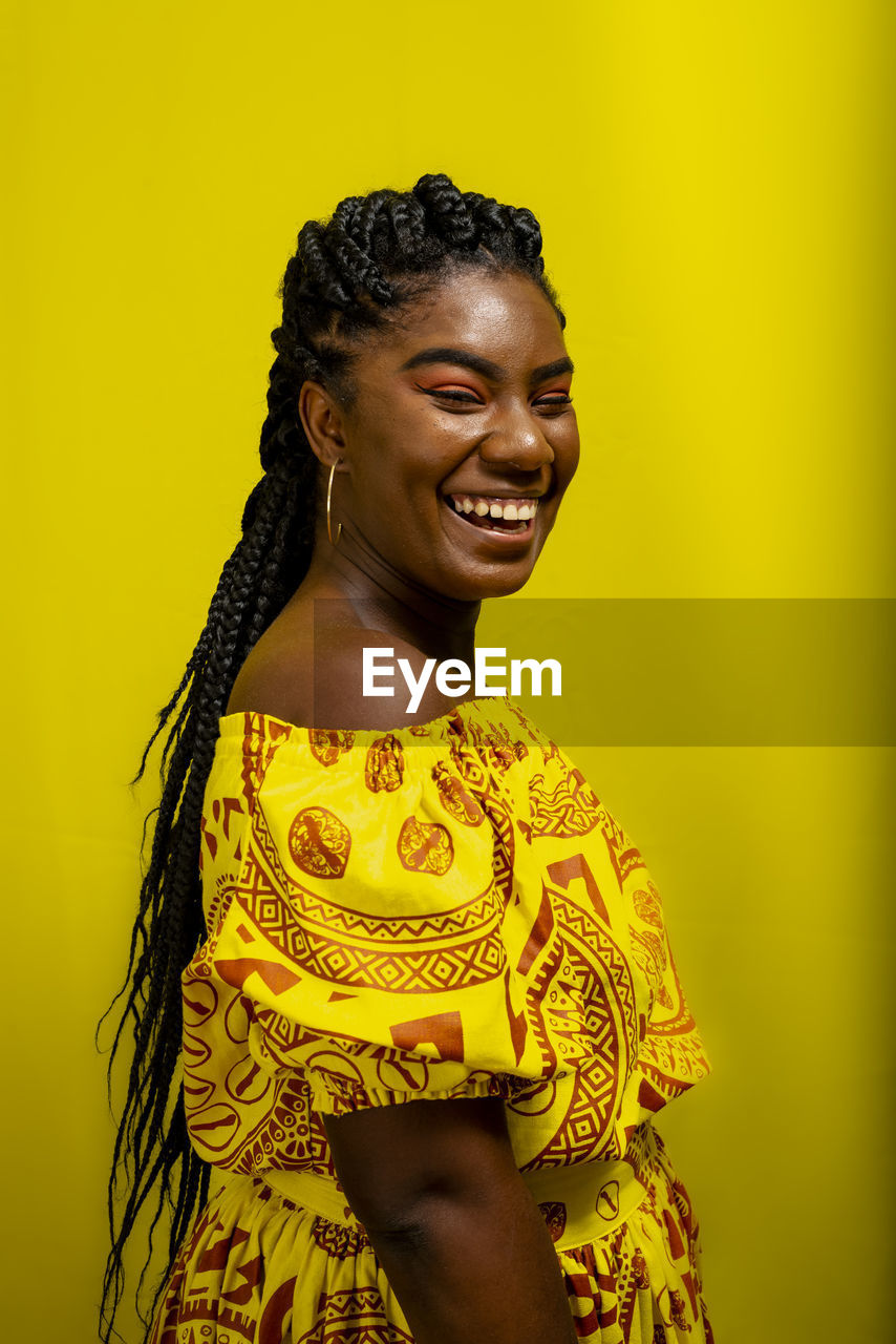 Young woman wearing colorful long clothes over yellow background. natural expression.