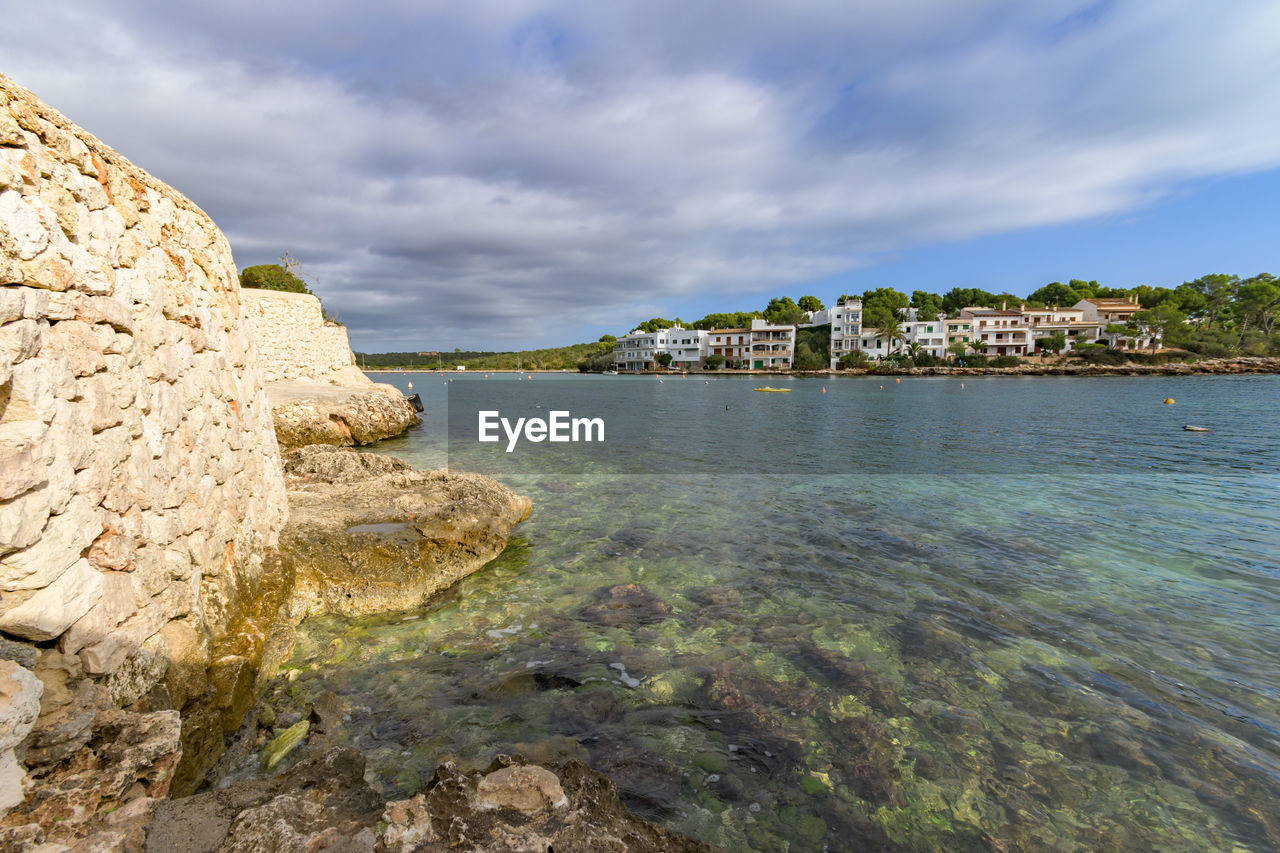 water, sea, sky, coast, land, shore, beach, cloud, nature, rock, travel destinations, scenics - nature, beauty in nature, coastline, travel, environment, architecture, body of water, landscape, ocean, terrain, cliff, tourism, tranquility, trip, vacation, no people, holiday, bay, outdoors, built structure, island, seascape, cove, tranquil scene, water's edge, building exterior, city, idyllic, day, building, bay of water, tree, lagoon, summer, plant, blue, sand, tropical climate