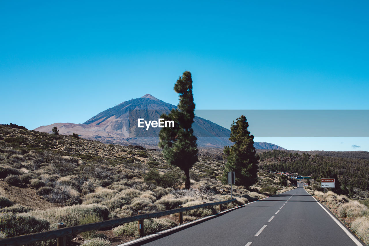 Road by mountains against clear blue sky