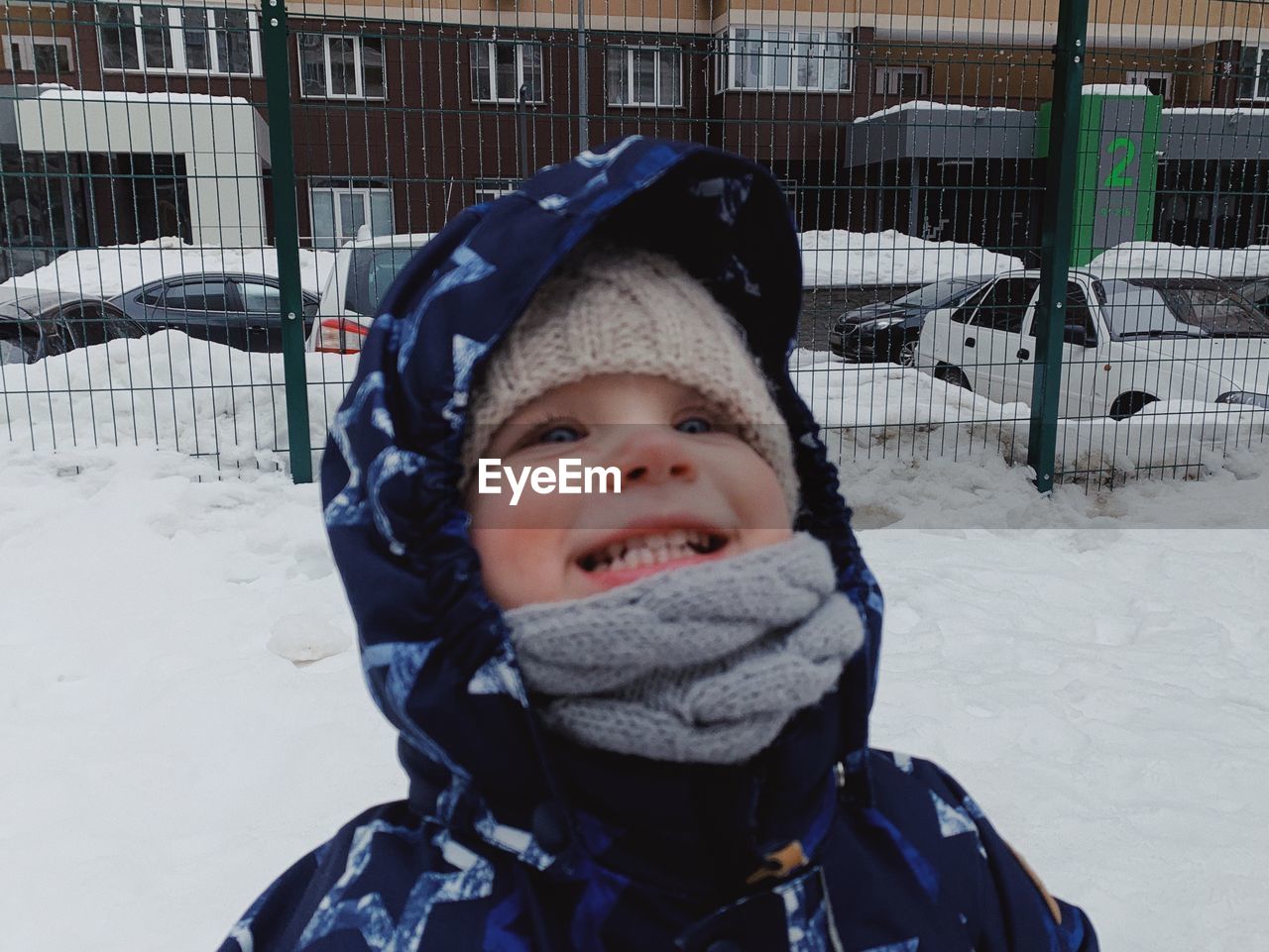 winter, cold temperature, snow, child, clothing, childhood, portrait, one person, warm clothing, smiling, hat, happiness, looking at camera, knit hat, nature, day, leisure activity, front view, emotion, men, toddler, fun, headshot, outdoors, cute, innocence, enjoyment, cheerful, lifestyles, glove, sports, frozen, winter coat, white, standing, fence, coat, female, jacket