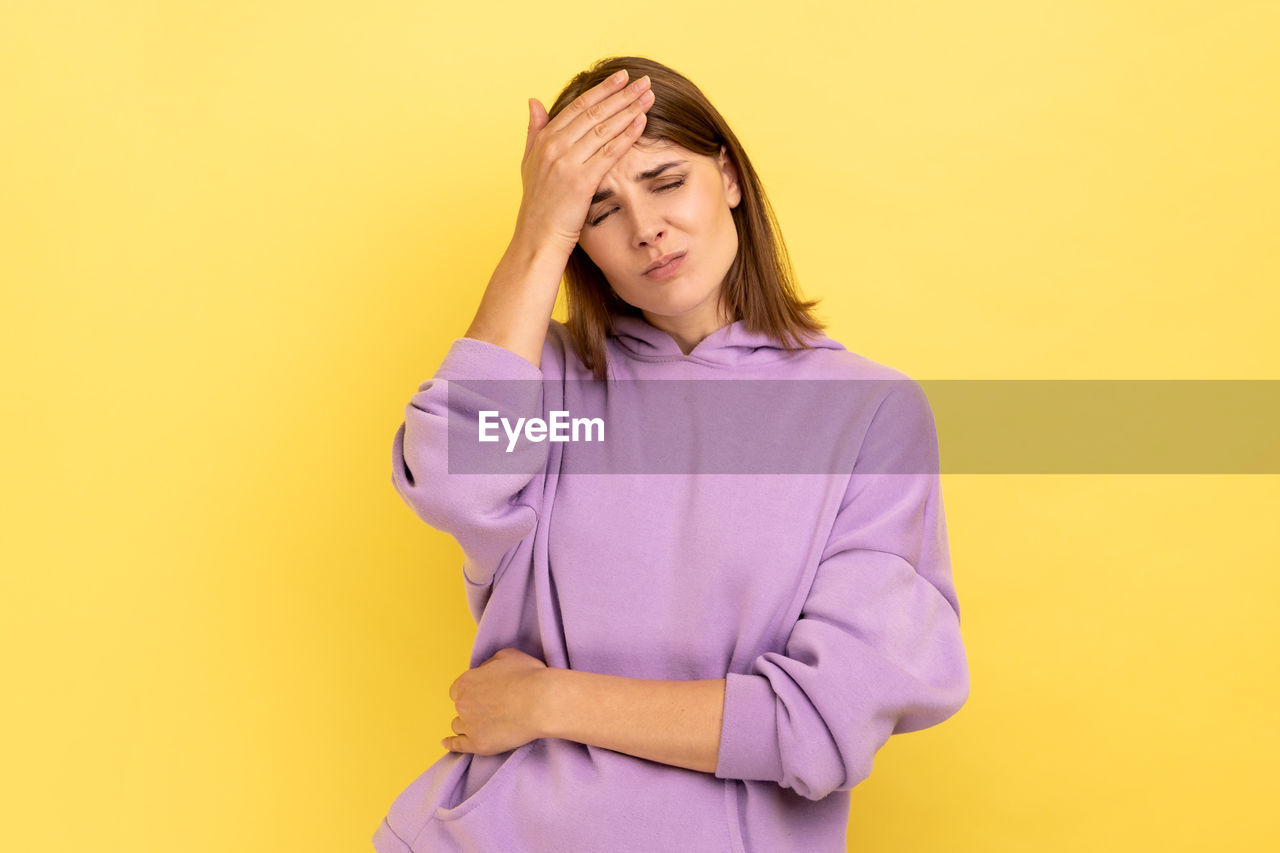 portrait of beautiful young woman against yellow background