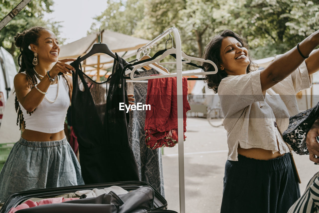 Smiling women buying dress at flea market