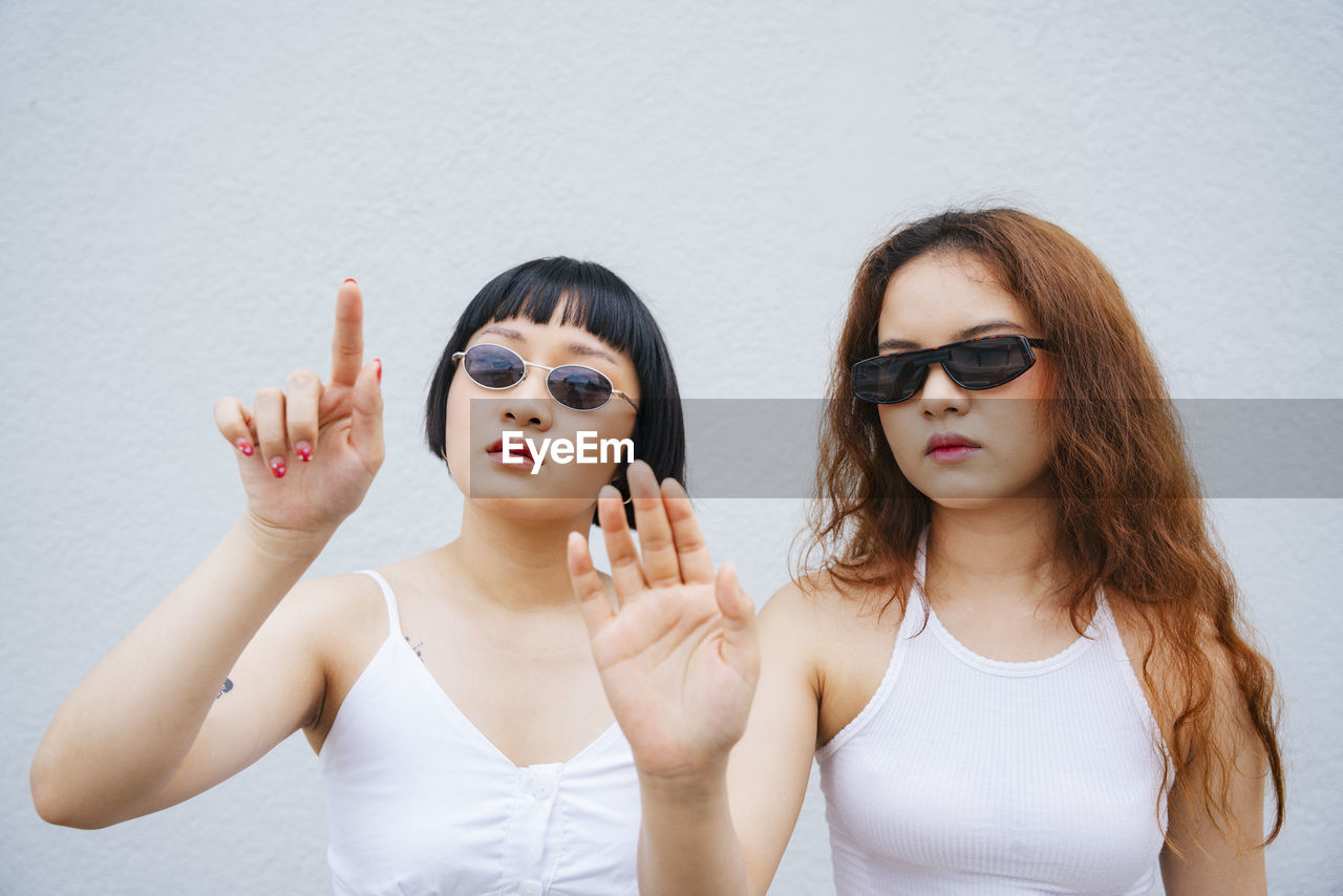 Lesbian couple gesturing while standing against wall outdoors