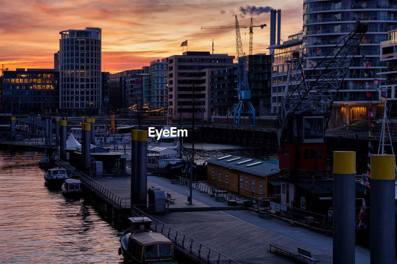 HIGH ANGLE VIEW OF RIVER AMIDST BUILDINGS AGAINST SKY AT SUNSET