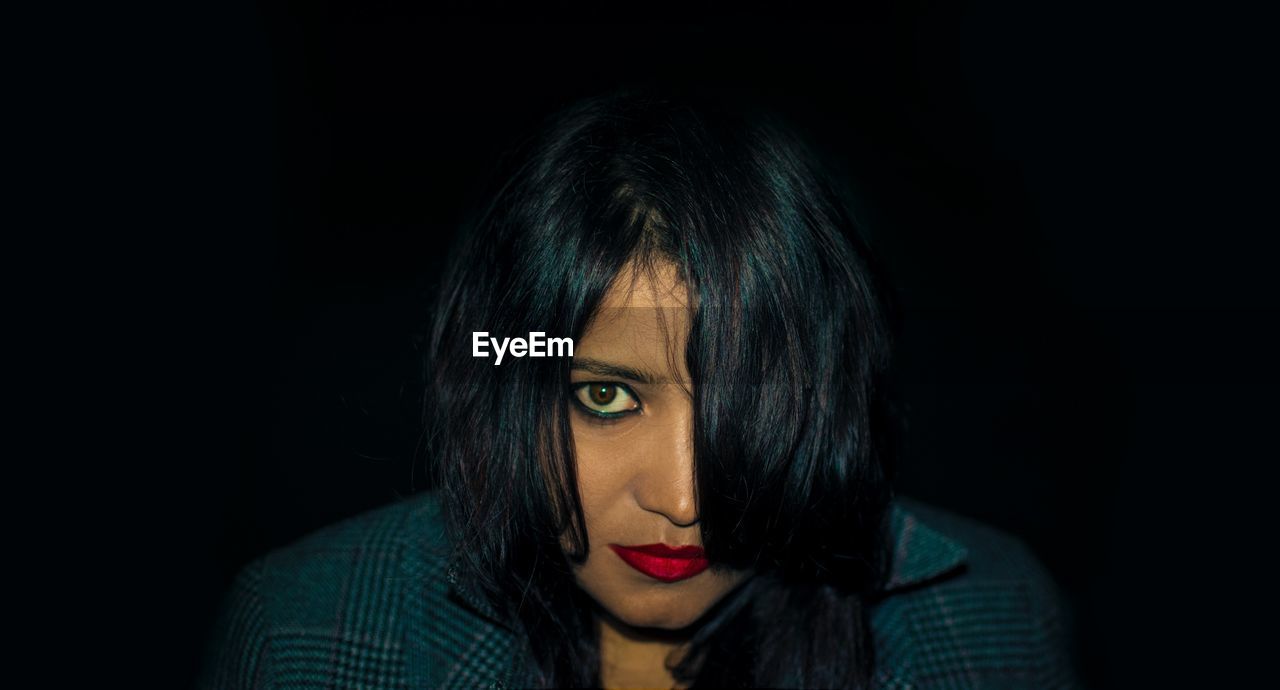 Close-up portrait of woman against black background