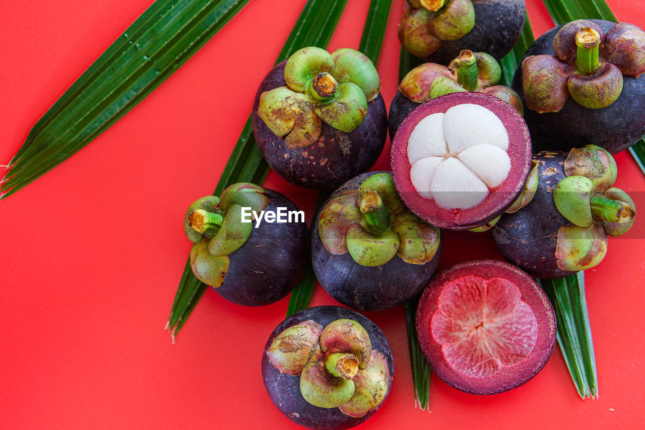 HIGH ANGLE VIEW OF FRUITS ON TABLE AGAINST RED BACKGROUND