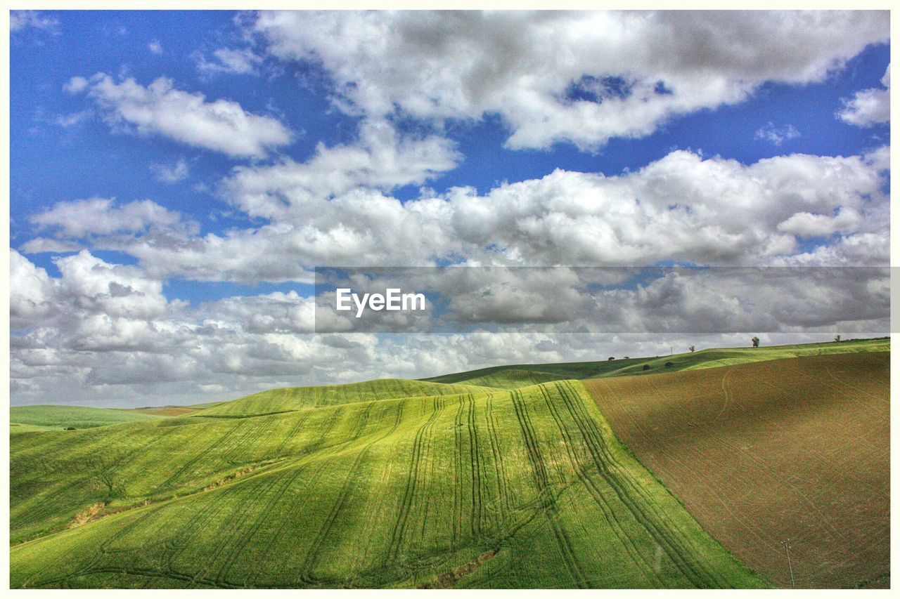 View of field against cloudy sky