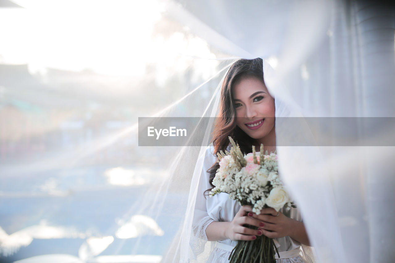 Portrait of smiling beautiful bride holding bouquet during wedding