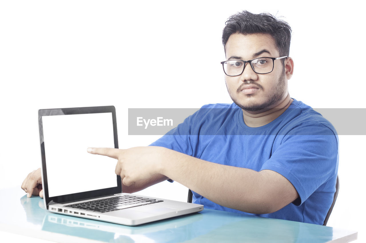 computer, technology, wireless technology, laptop, eyeglasses, communication, using laptop, glasses, one person, adult, men, internet, writing, business, computer network, person, indoors, casual clothing, computer equipment, young adult, looking, table, portrait, typing, sitting, white background, working, e-mail, portability, learning, furniture, front view, businessman, business finance and industry, using computer, office, relaxation, conversation, desk, occupation, studio shot