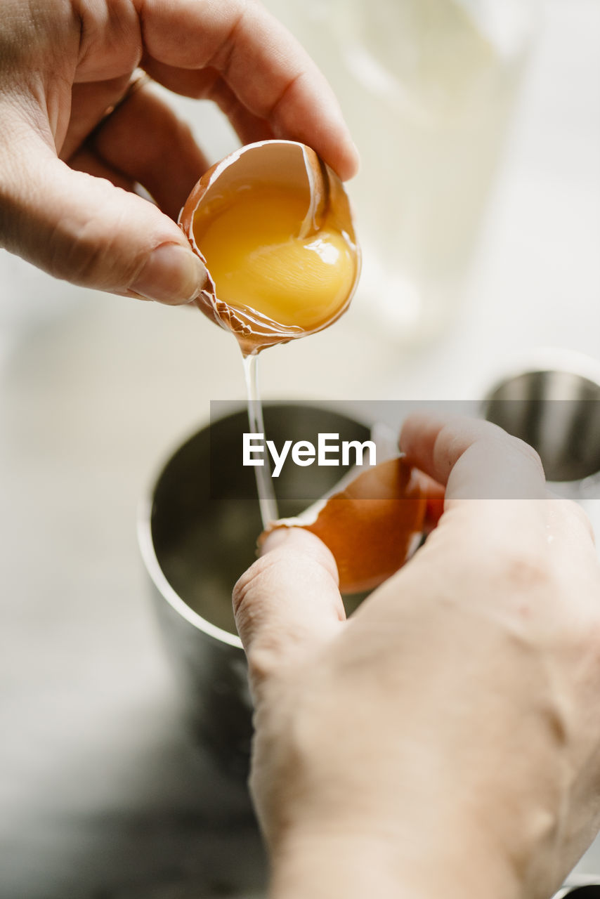 Close-up of woman breaking egg in drinking glass