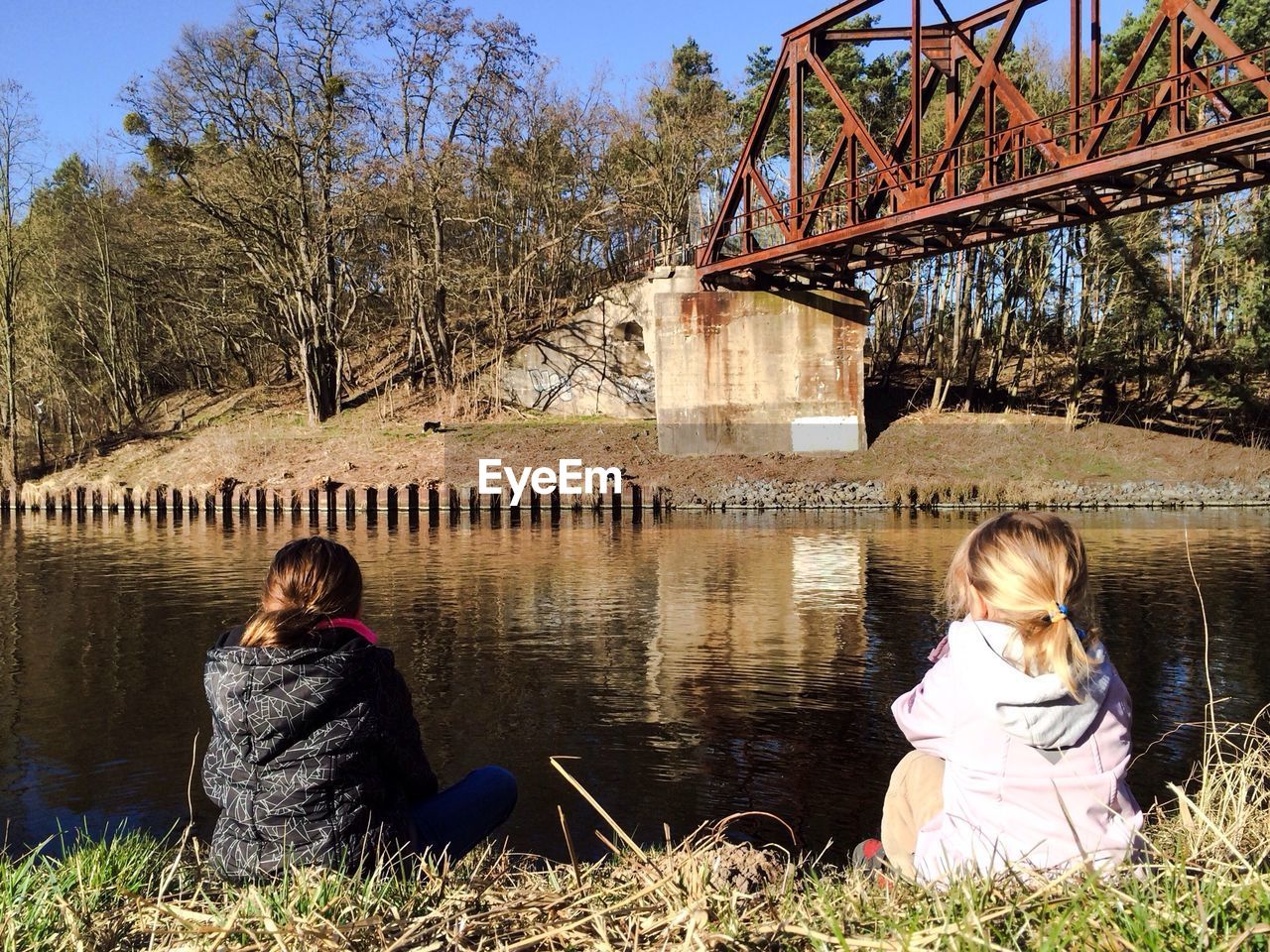 Rear view of child sitting by river