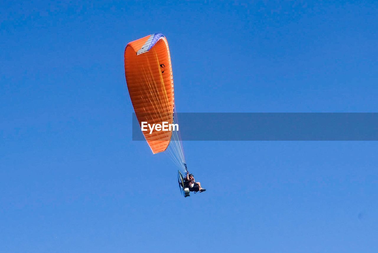 Low angle view of person paragliding against clear blue sky