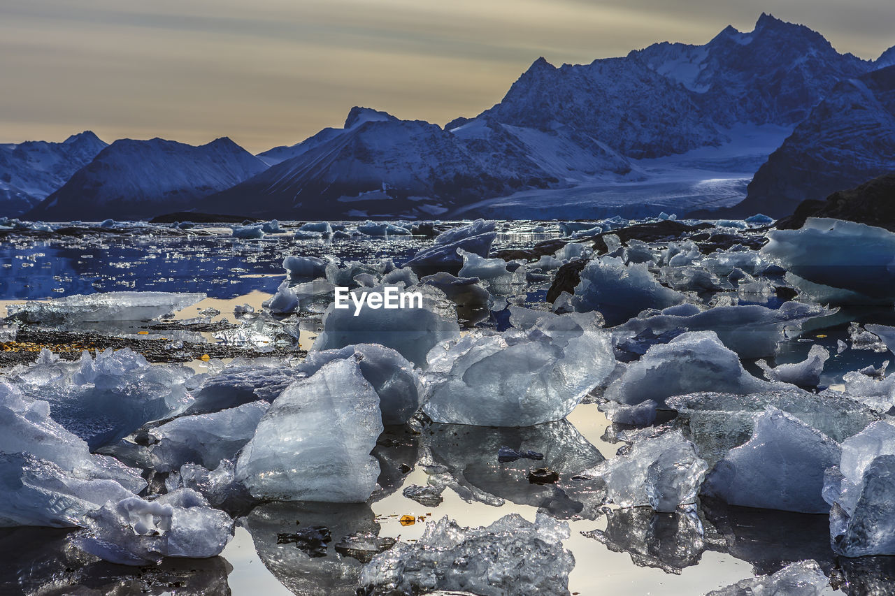 View of ice in frozen lake against mountain range