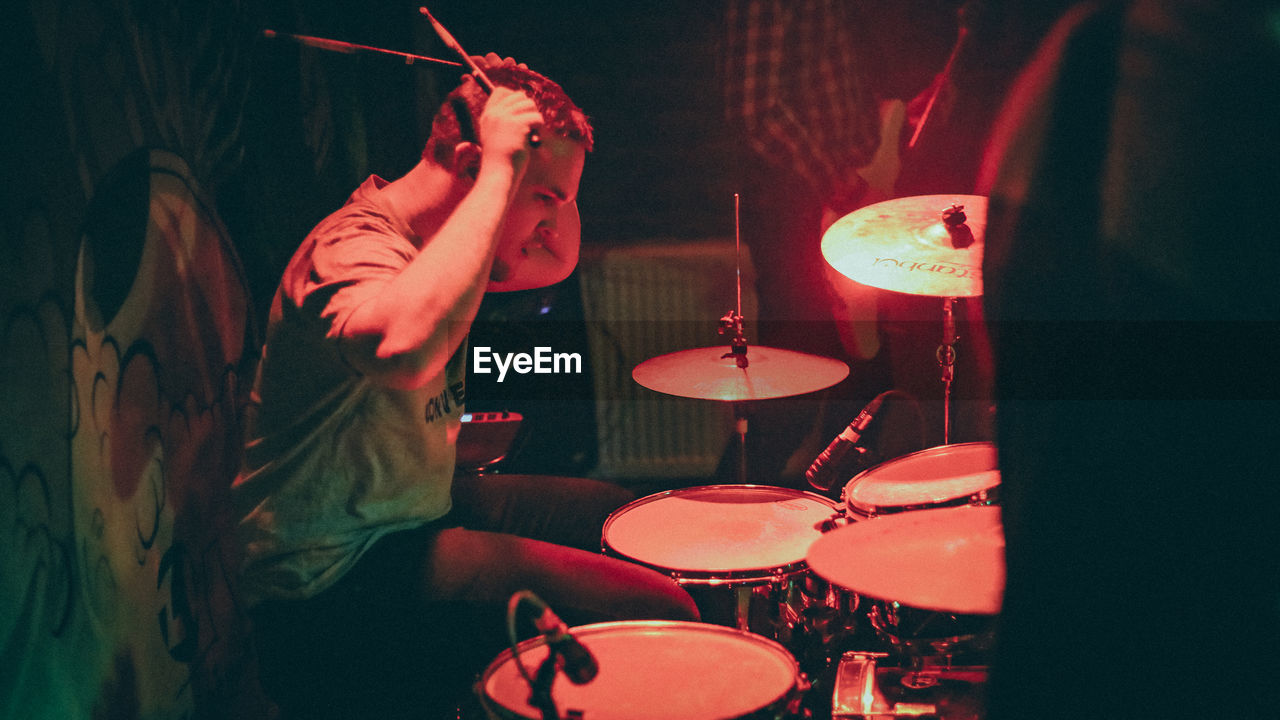 Side view of man playing drum in concert