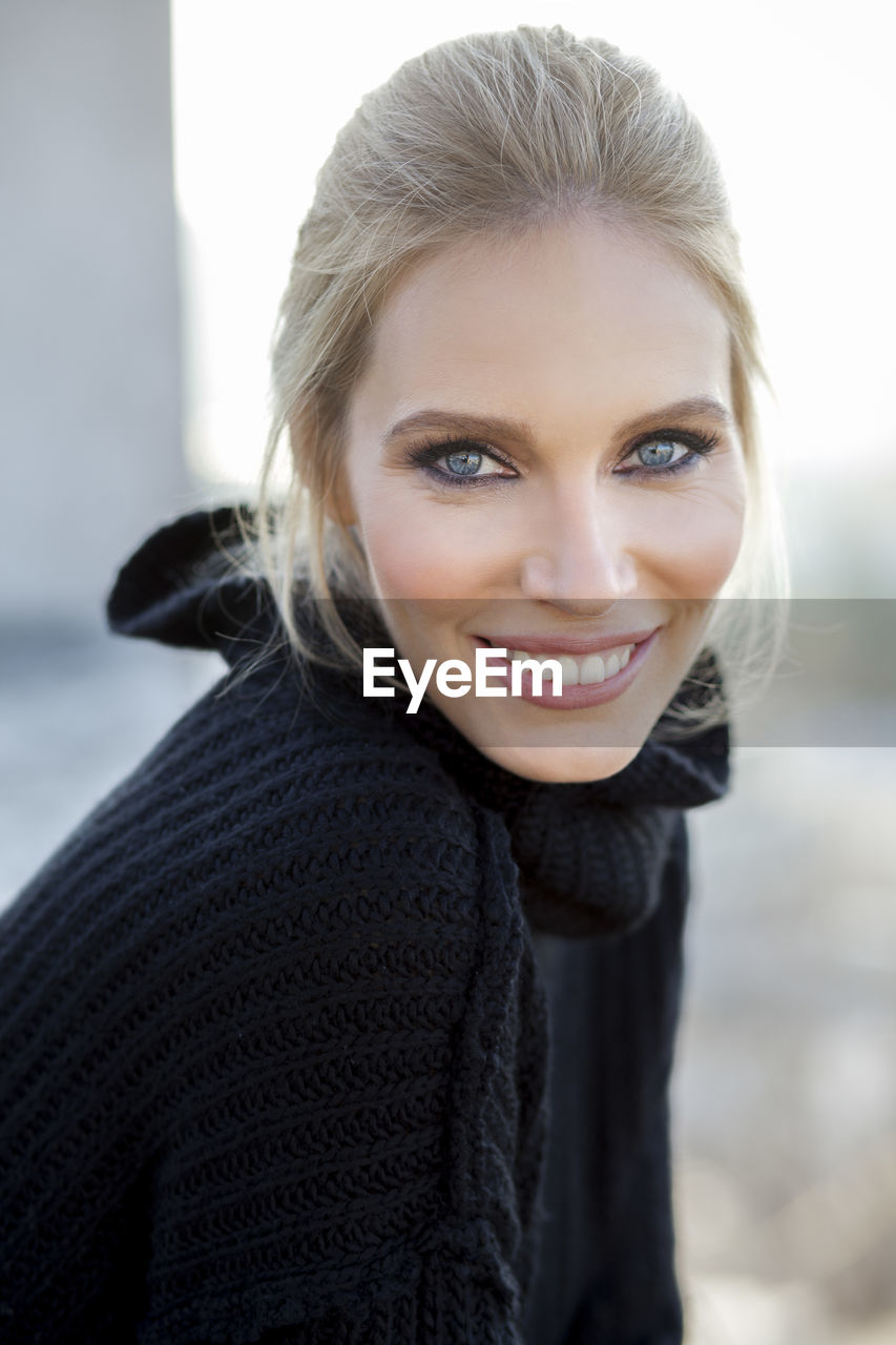 Side view portrait of beautiful woman smiling against sky