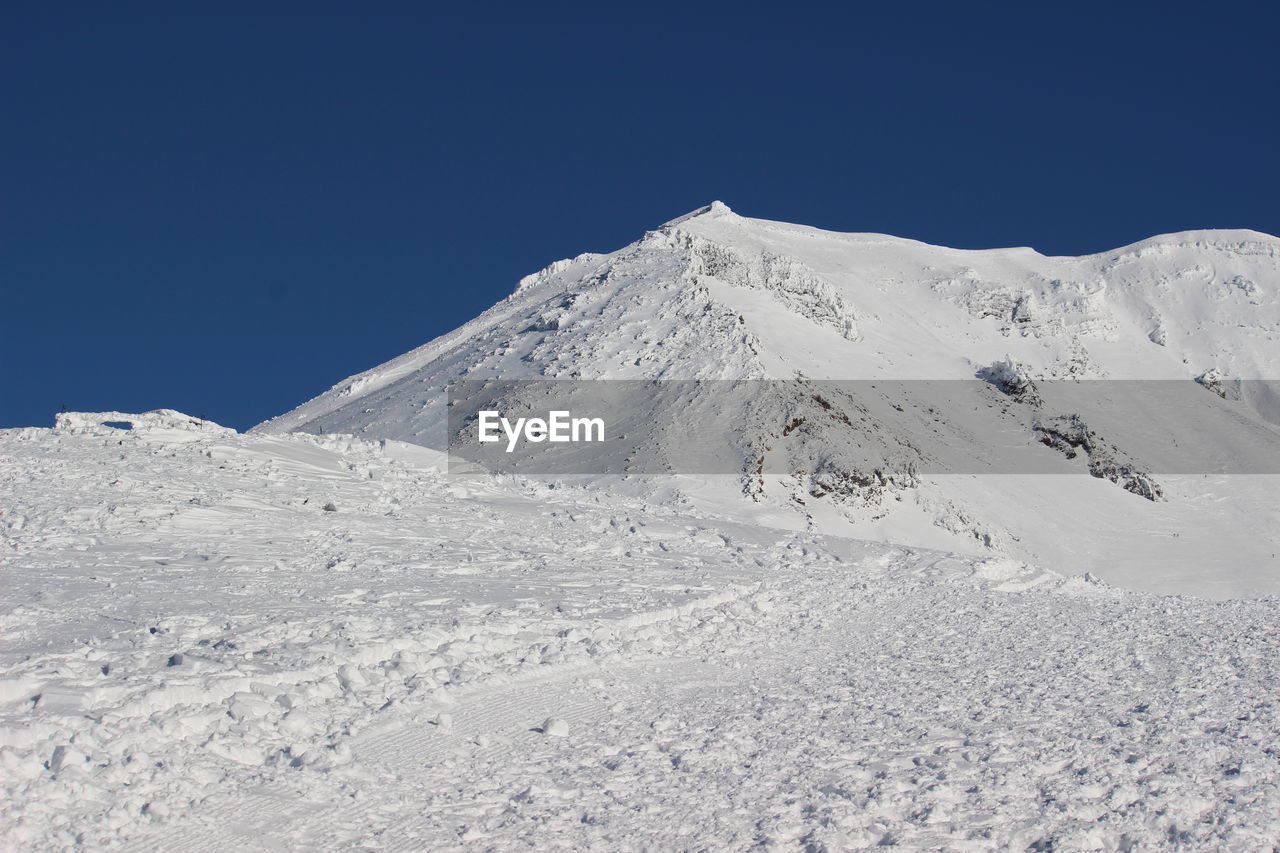 Snow covered mountain against blue sky