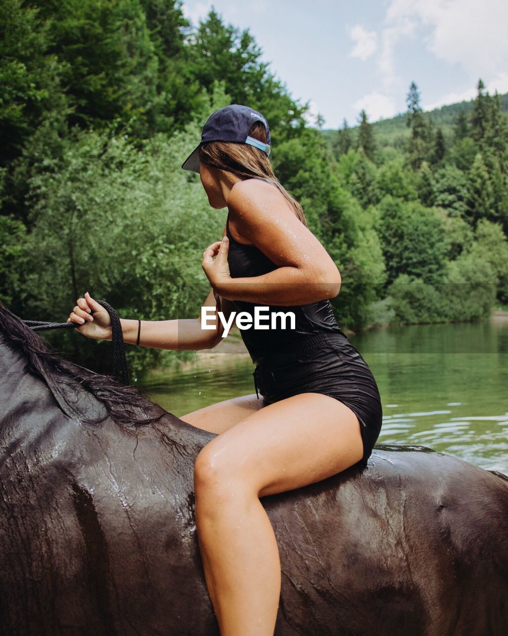 WOMAN SITTING ON LAKE AGAINST TREES