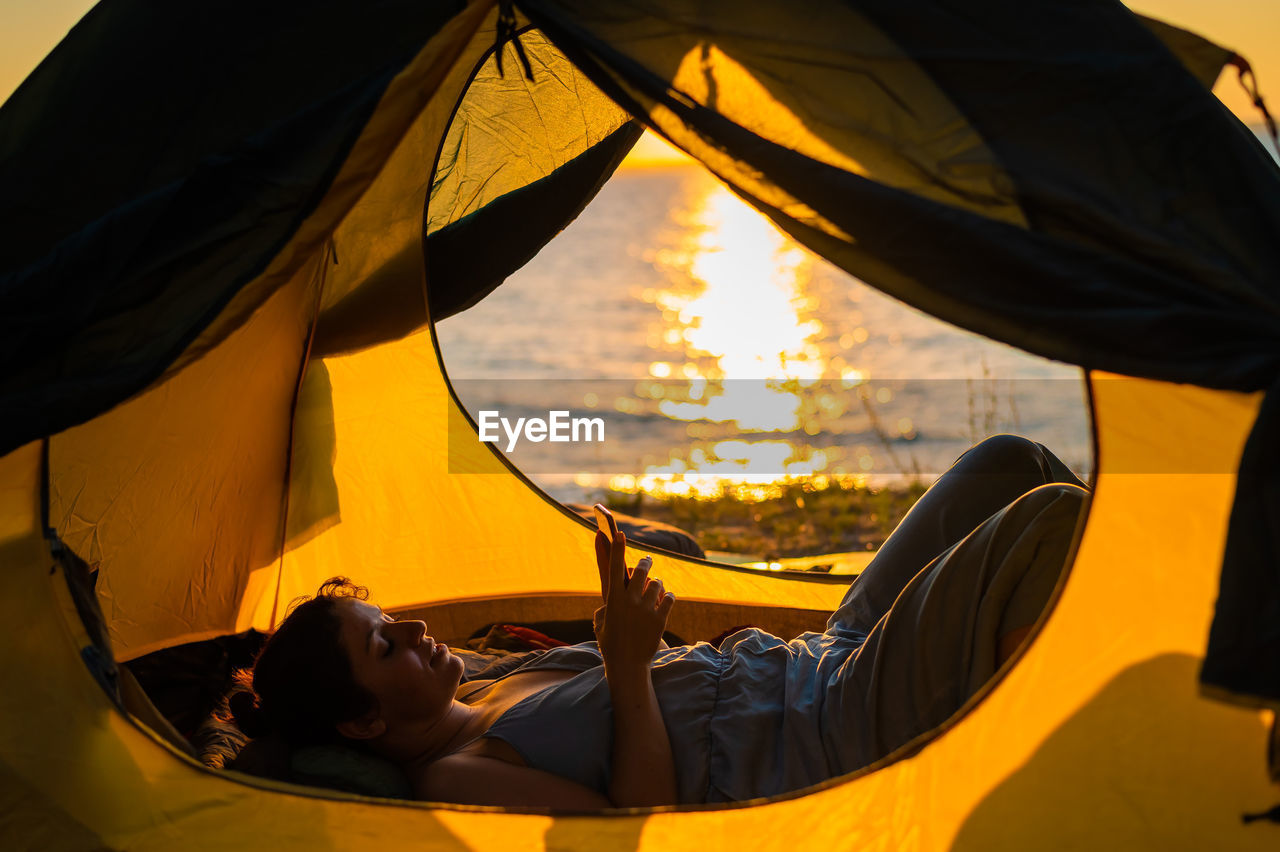 Rear view of woman lying on orange during sunset