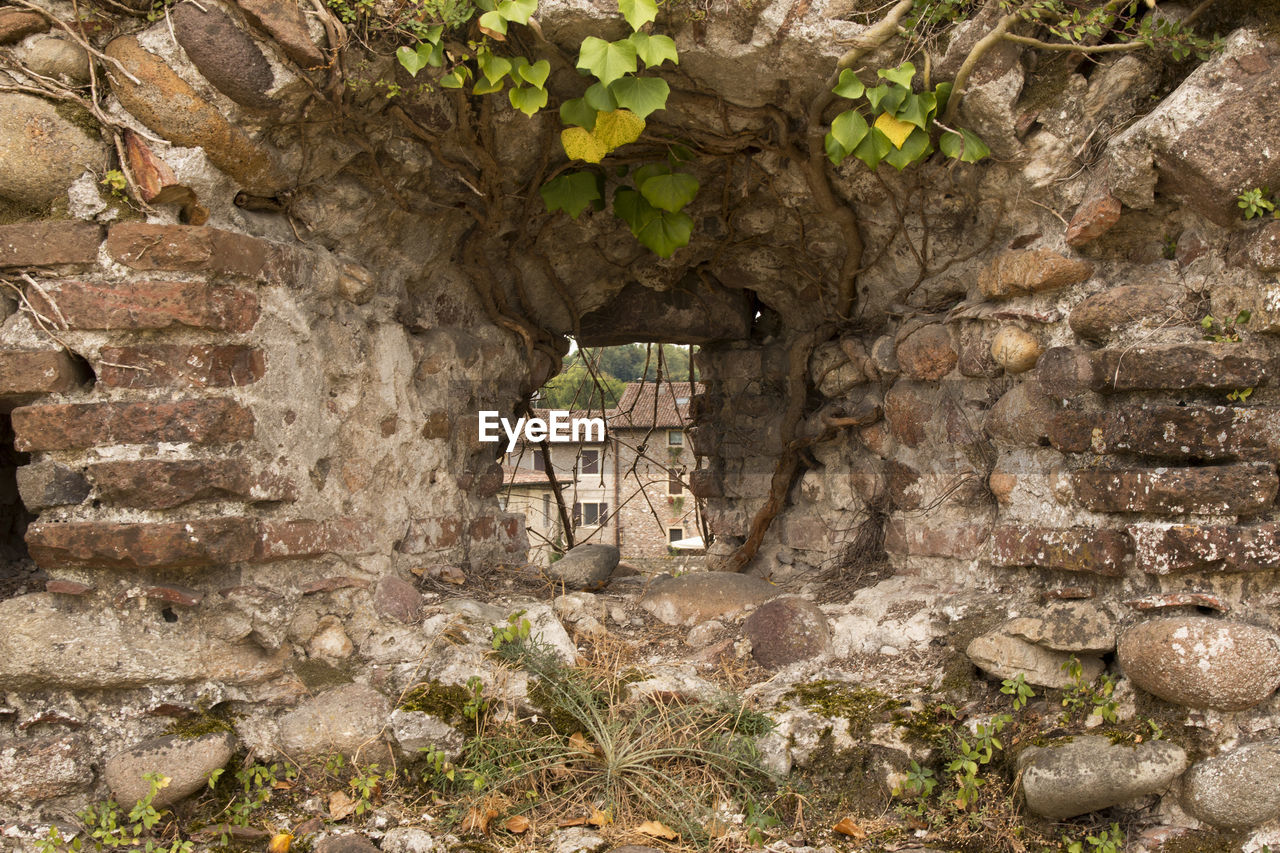 Building seen through hole in stone wall