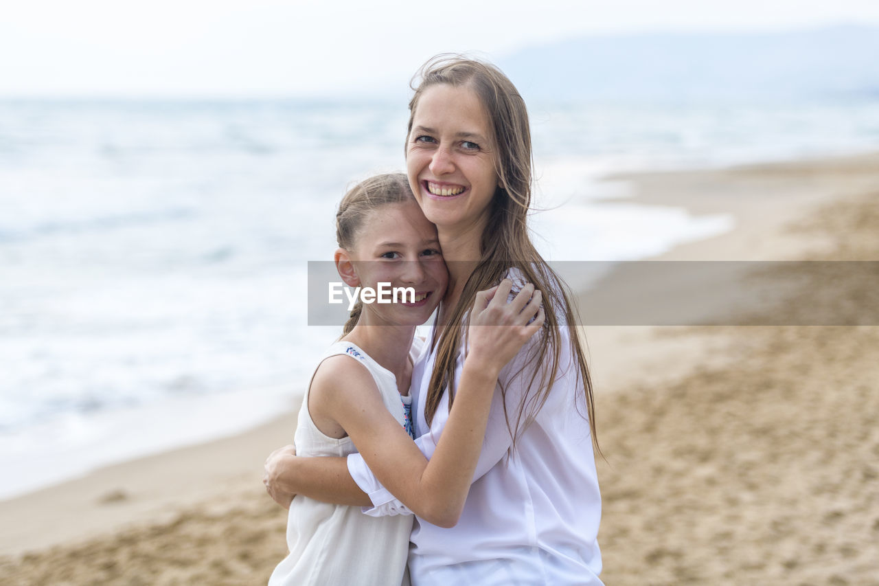 Portrait of mother with daughter standing at beach
